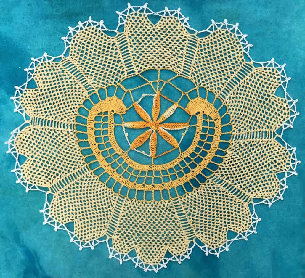 A yellow crochet doily on a teal background