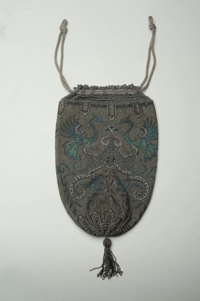 A beaded drawstring purse with peacock design, grey background with turquoise detail