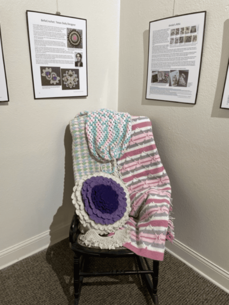 Multicolored rocheted objects, pillow, collar, blankets and bag on a wooden chair in the Texas Crochet History exhibit