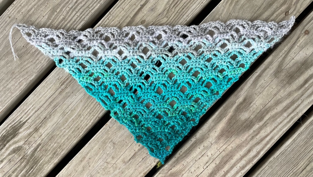A crocheted shawl in shades of teal and grey