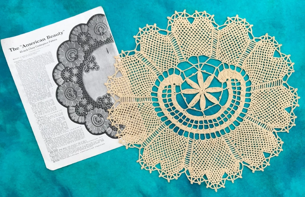 A crocheted doily on a teal background next to a historical knit pattern