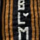 A black knitted banner with yellow stripes and the letters BLM knit in white