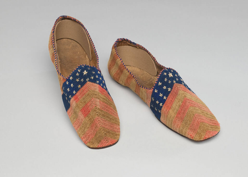 A pair of hand made shoes with red and tan alternating stripes and a section of blue stars