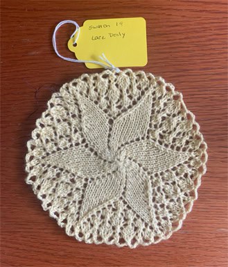 Handmade knit and crochet doily with floral pattern on wooden surface.