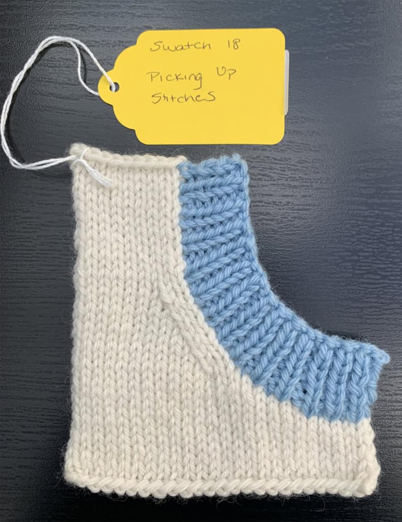 A knitted sample with three main parts of a neckline is knitted in white yarn. Ribbing is knitted into the neckline edge in light blue yarn.